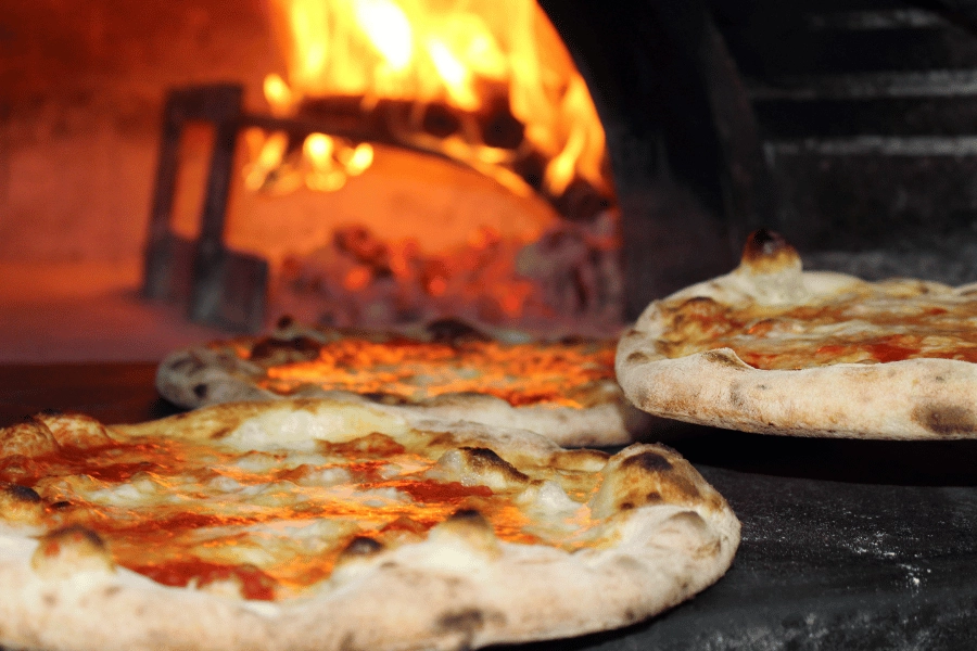 three pizzas in a wood fire pizza oven 